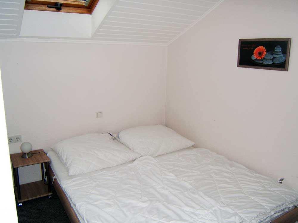 Schlafzimmer 1 (Dachgeschoss): Doppelbett (1,6 x 2 m) mit Beistelltischchen, Kleiderschrank