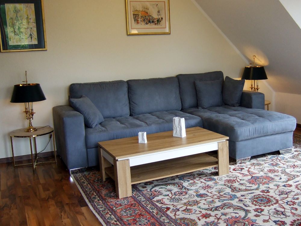 Wohnraum mit Essplatz, Fernseher, gemütlicher Couch und Sessel, CD-Player, großer Balkon mit Gartenmöbel